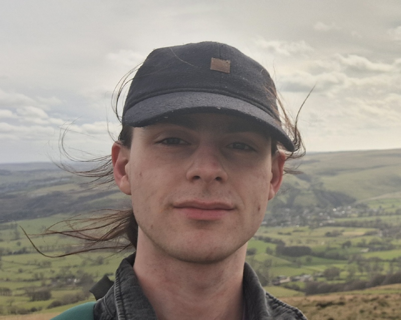 A photo of me up a hill. I'm wearing a cap and my hair is all over the place.